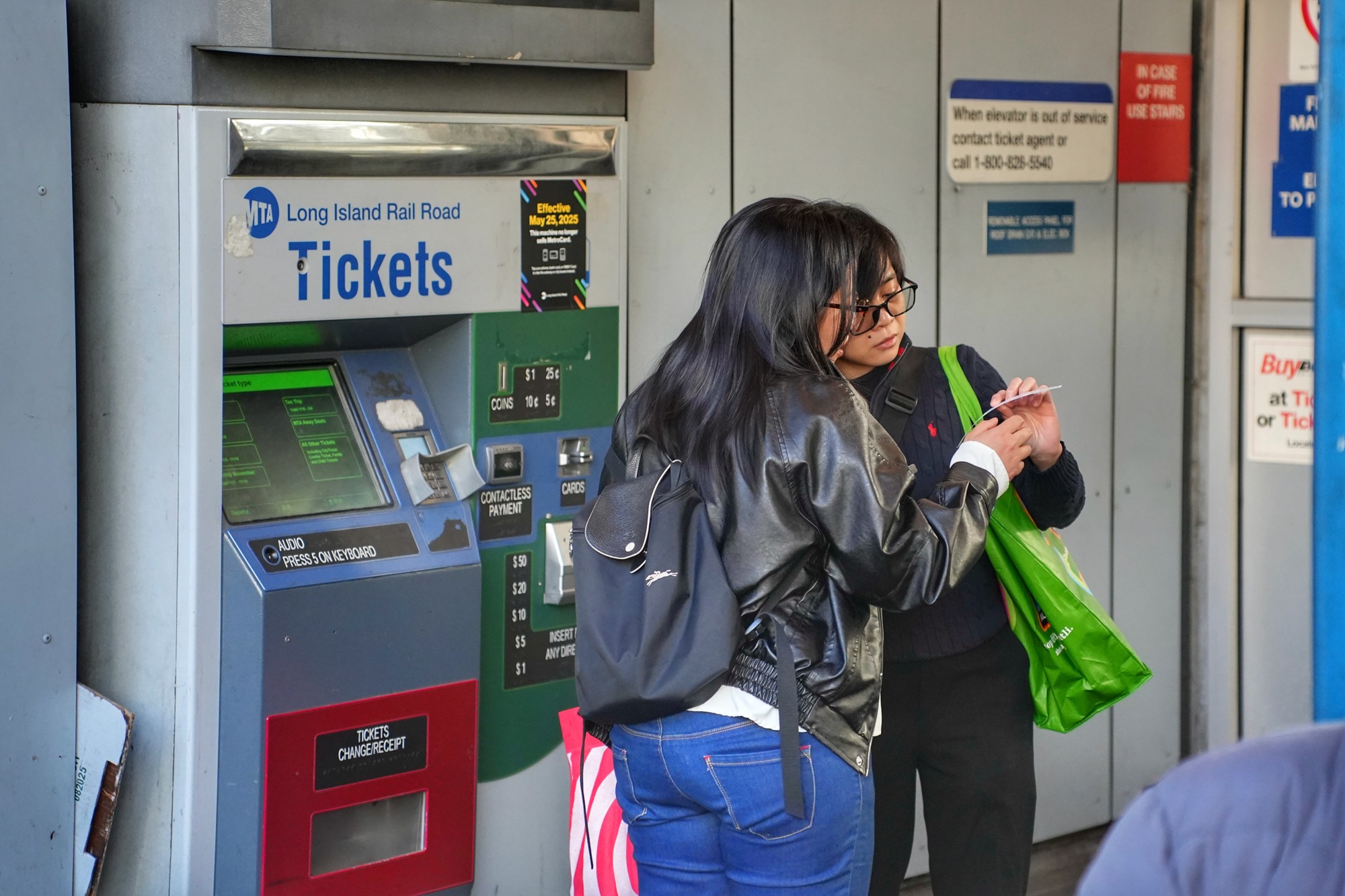 Two women check ticket information outside the Long Island Rail Road station. Nov. 8, 2025.