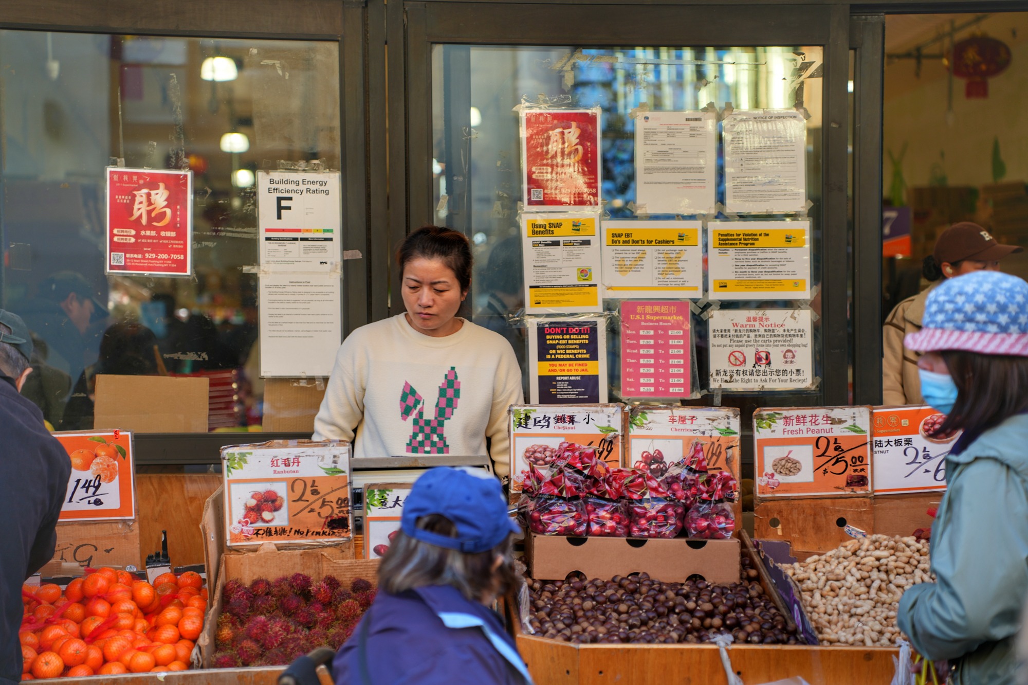 A woman sells fruit from a sidewalk stand outside a supermarket. Nov. 8, 2025.
