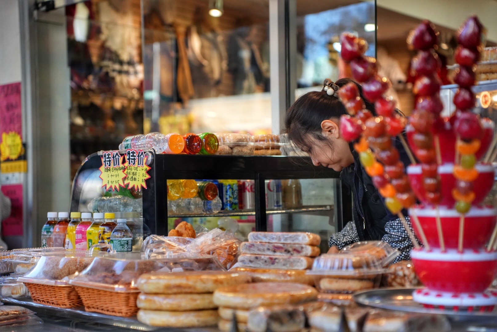 A vendor works behind a sidewalk display of snacks and bottled drinks. Nov. 8, 2025.