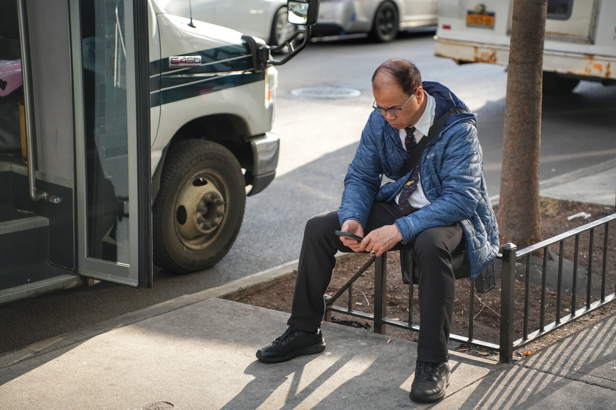 A bus driver waits for passengers while looking at his phone. Nov. 8, 2025.