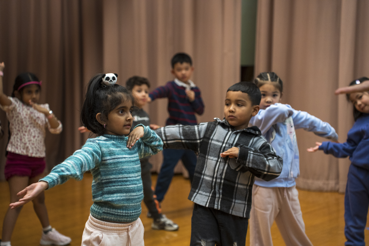 After watching Tang demonstrate, the children try the movement together.