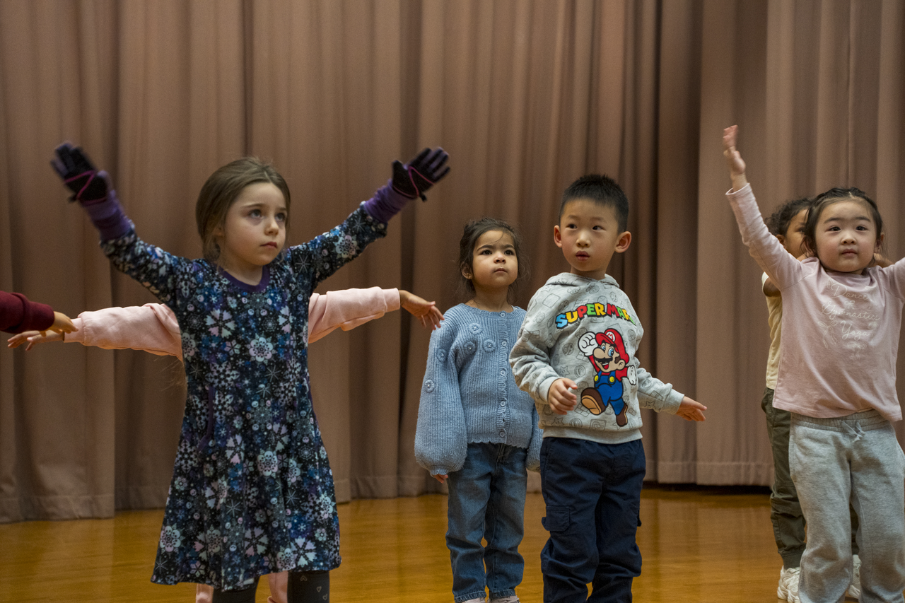 Children extend their arms and work through the gesture.