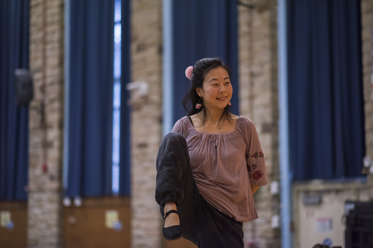 Tang demonstrates a raised-leg position as the children wait for the next cue.