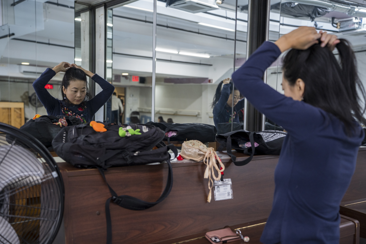 Between classes, Tang reties her hair in the mirror.