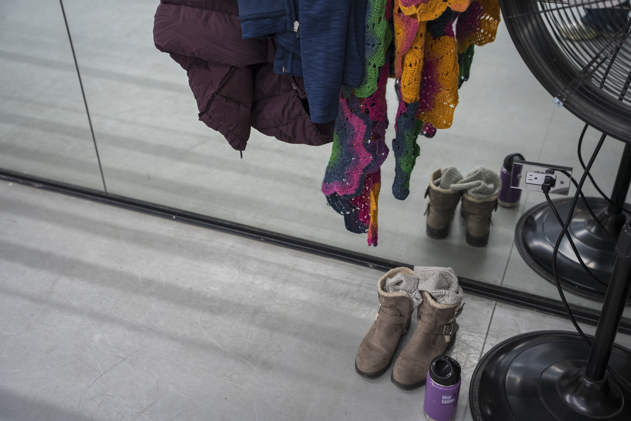 Tang’s coat, shoes, and water bottle rest beside the mirrored wall.