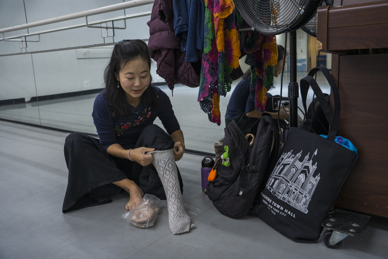 Between exercises, Tang crouches to help a student adjust a dance shoe.