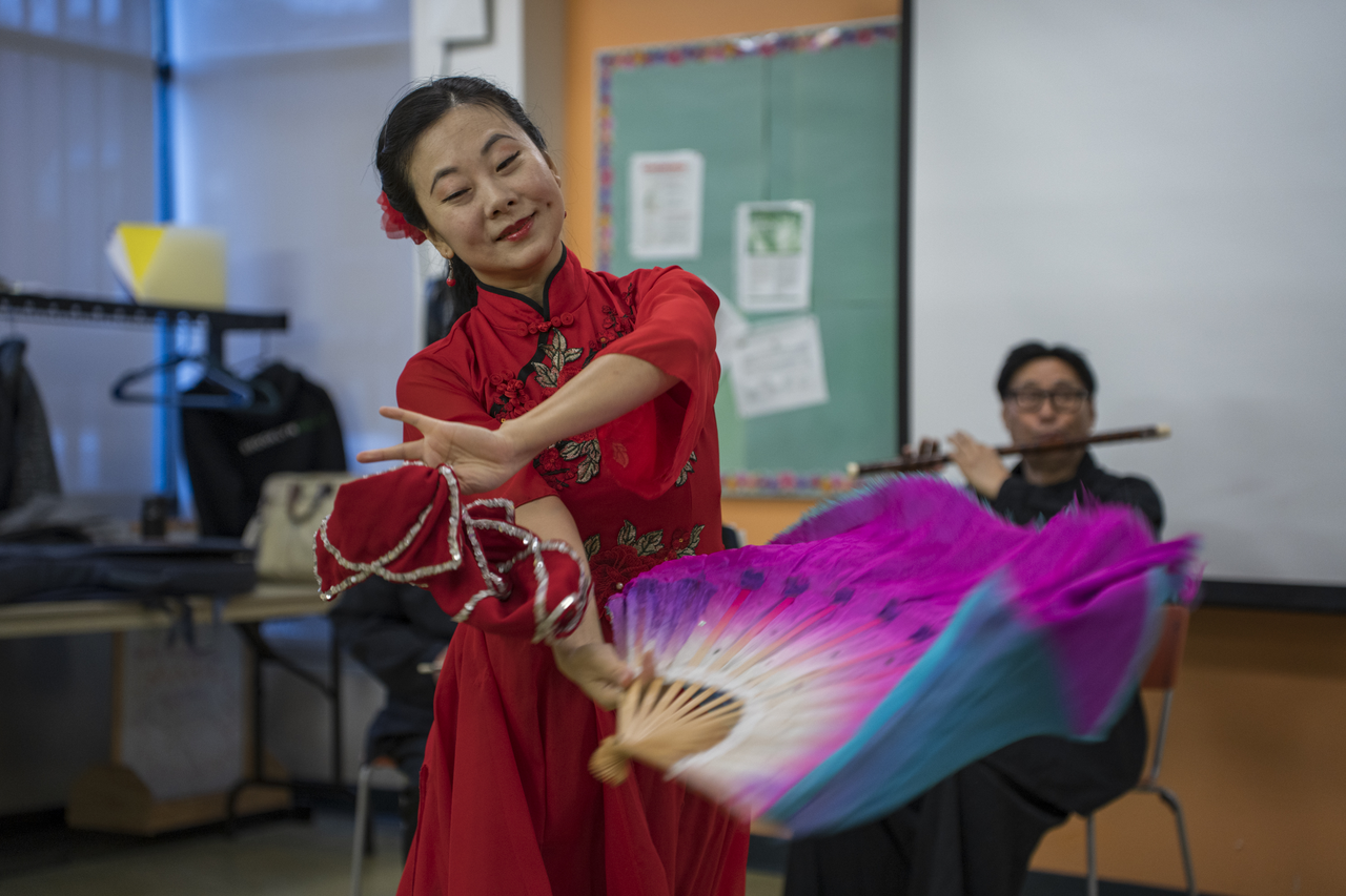 Tang dances with a fan while musicians accompany her.