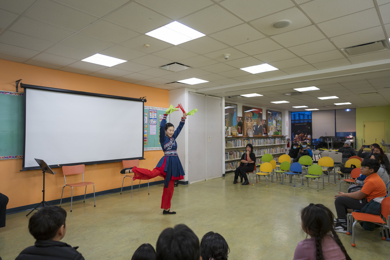 Tang performs in Mongolian-style dress as children watch from the floor.