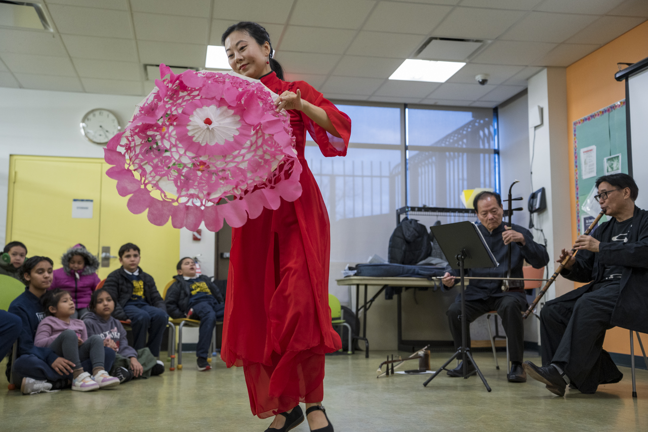 The audience sits on the floor and watches Tang perform.