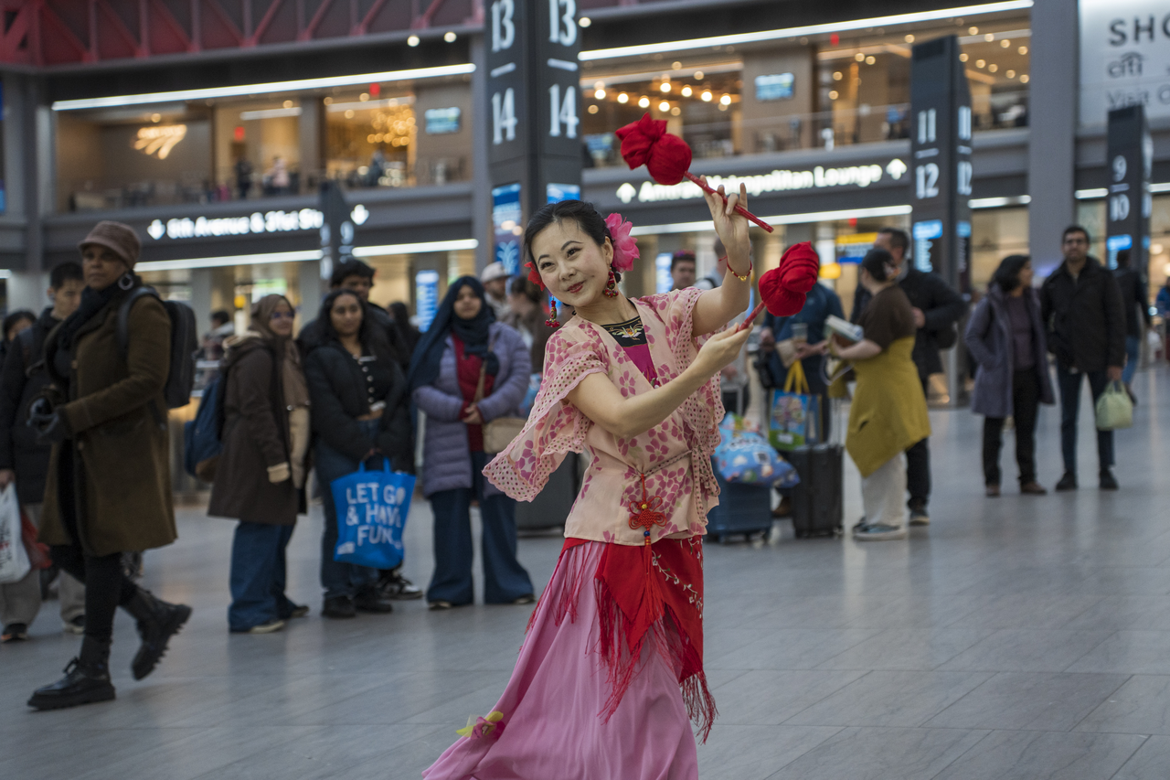 Tang dances in the Penn Station concourse as travelers stop to watch.