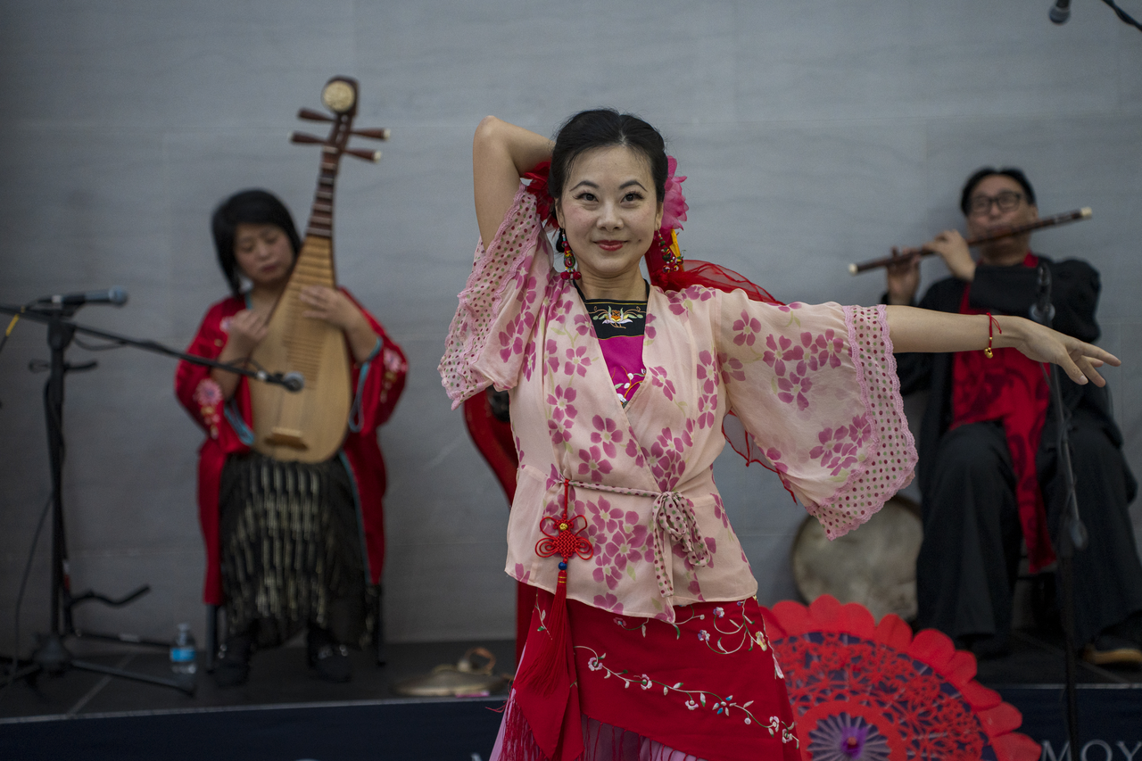 Tang holds a pose in front of the musicians.