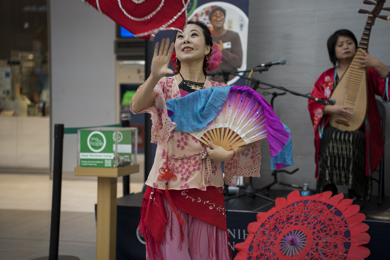Tang performs with a fan alongside musicians at Penn Station.