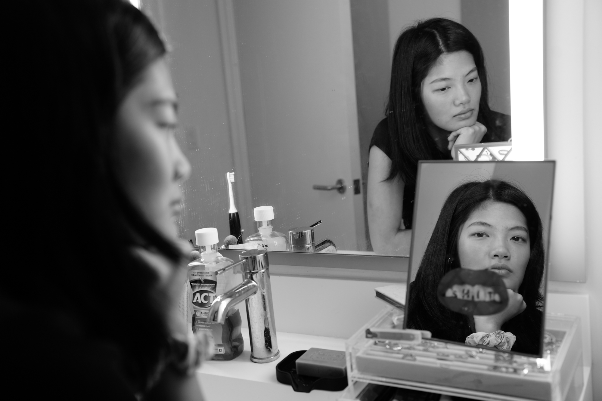 Rachel Zhong stands in her bathroom, reflected in both the wall mirror and the vanity mirror. Nov. 22, 2025.
