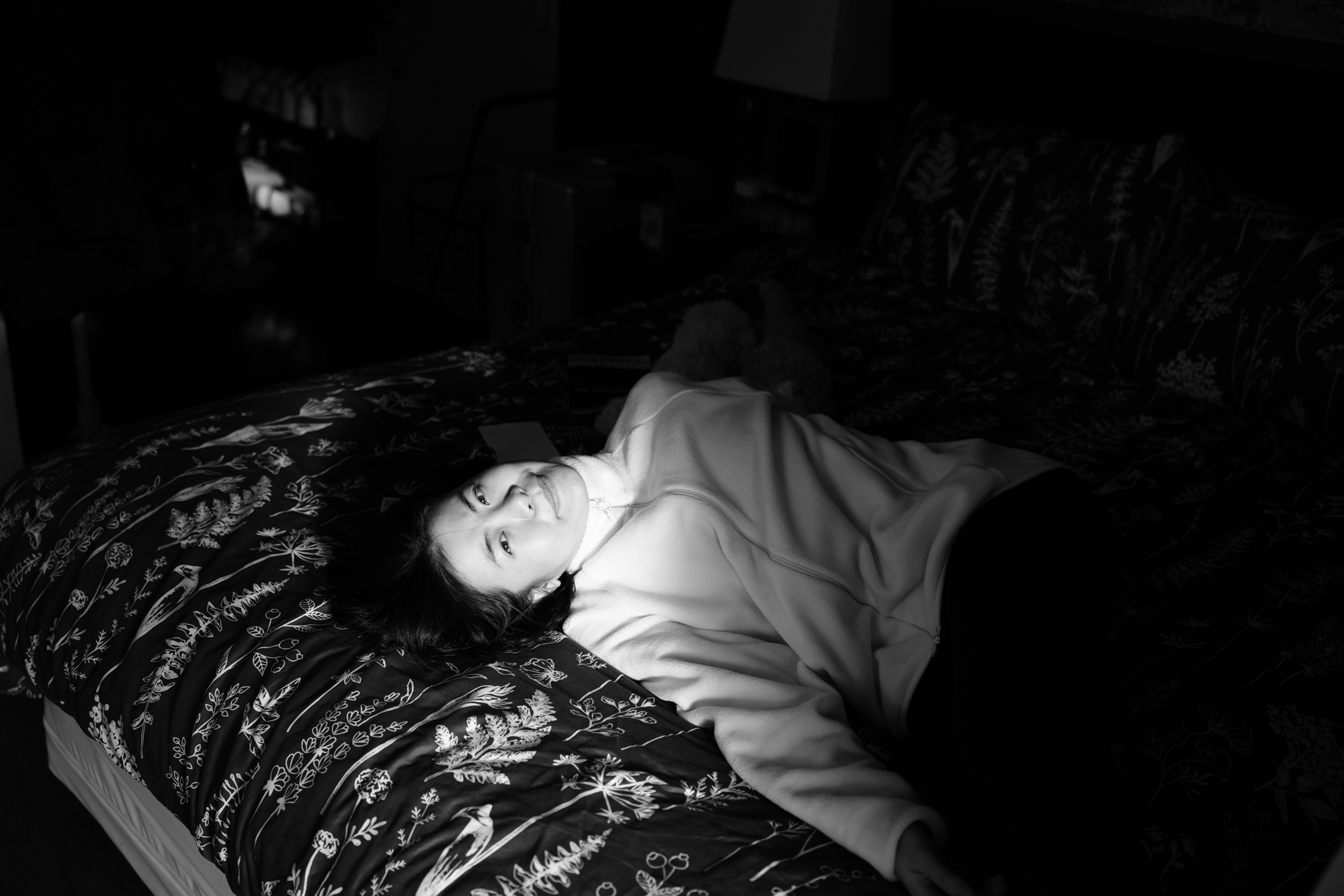 Afternoon light falls across Christine Cheng as she rests on her bed. Nov. 19, 2025.