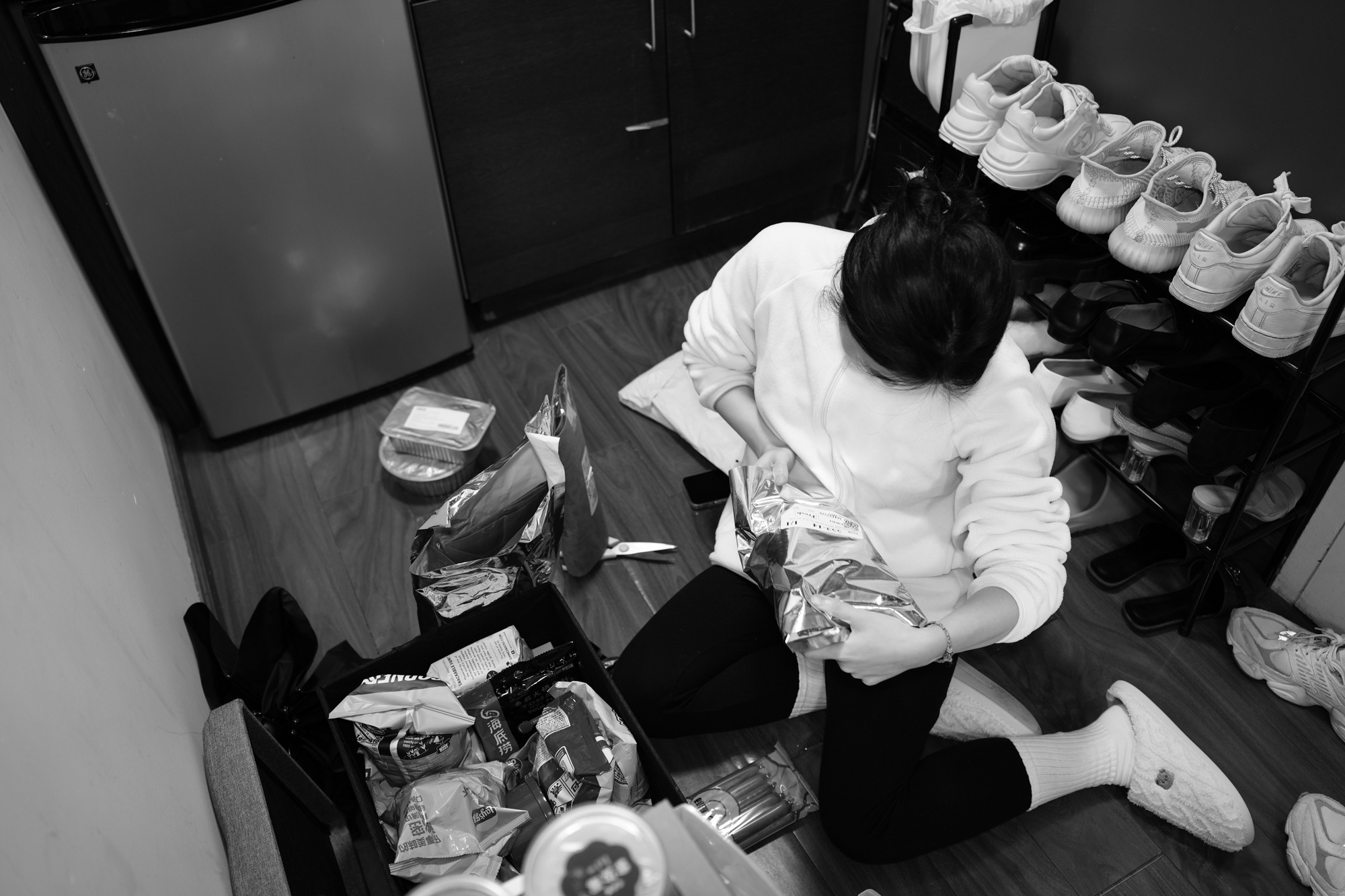 Christine Cheng kneels between the kitchen and entryway to open a package. Nov. 19, 2025.