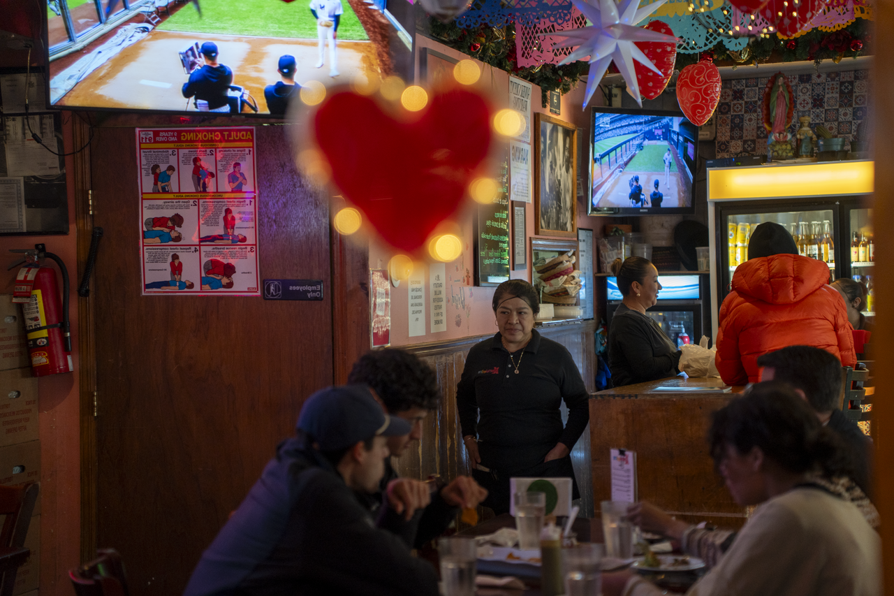 Dinner service begins beneath a heart-shaped neon sign as the room fills with conversation.