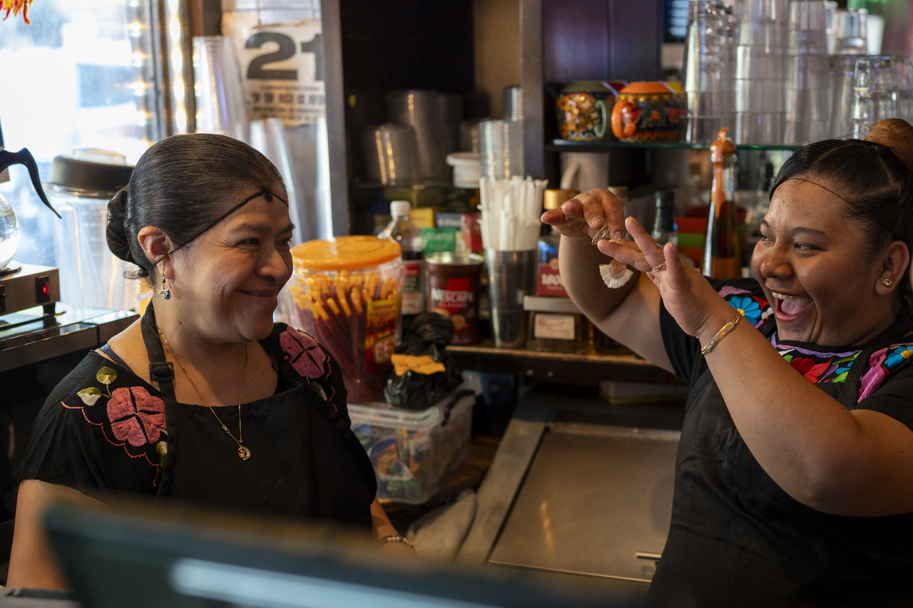 Behind the counter, the family embraces.
