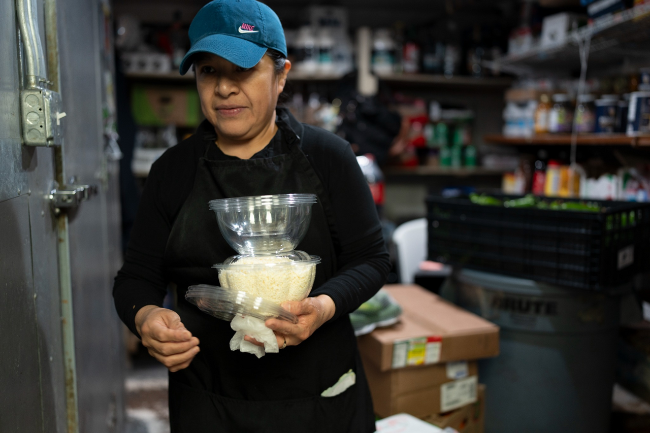 Before opening, an employee carries a stack of basins through the narrow stockroom.
