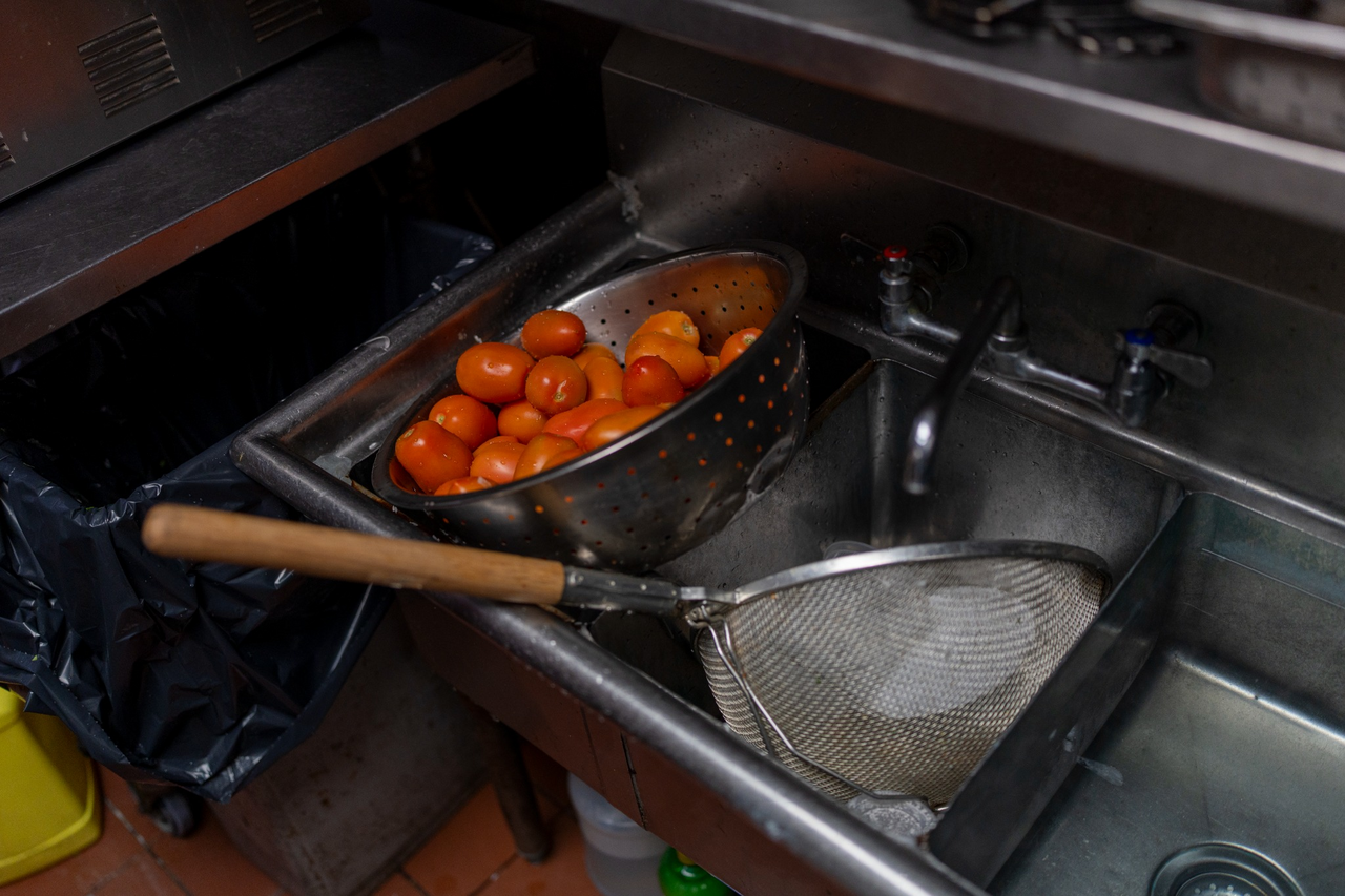 In the kitchen, Giovanni drains a large basin of tomatoes.