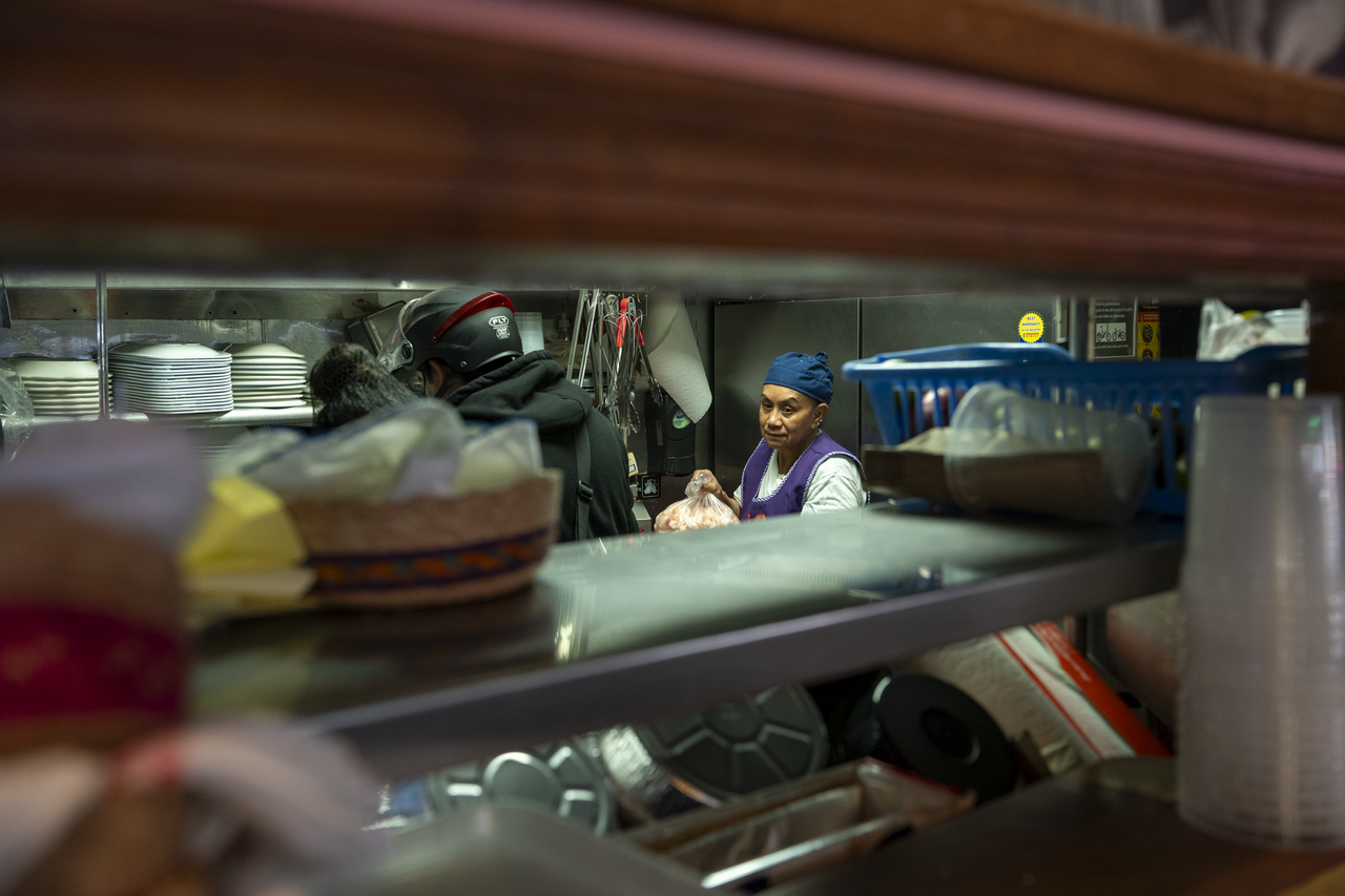 Kitchen staff pass finished dishes through the service window.