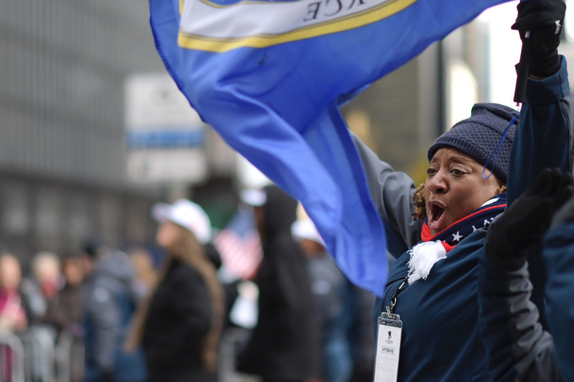 A parade participant raises a blue flag above the crowd.