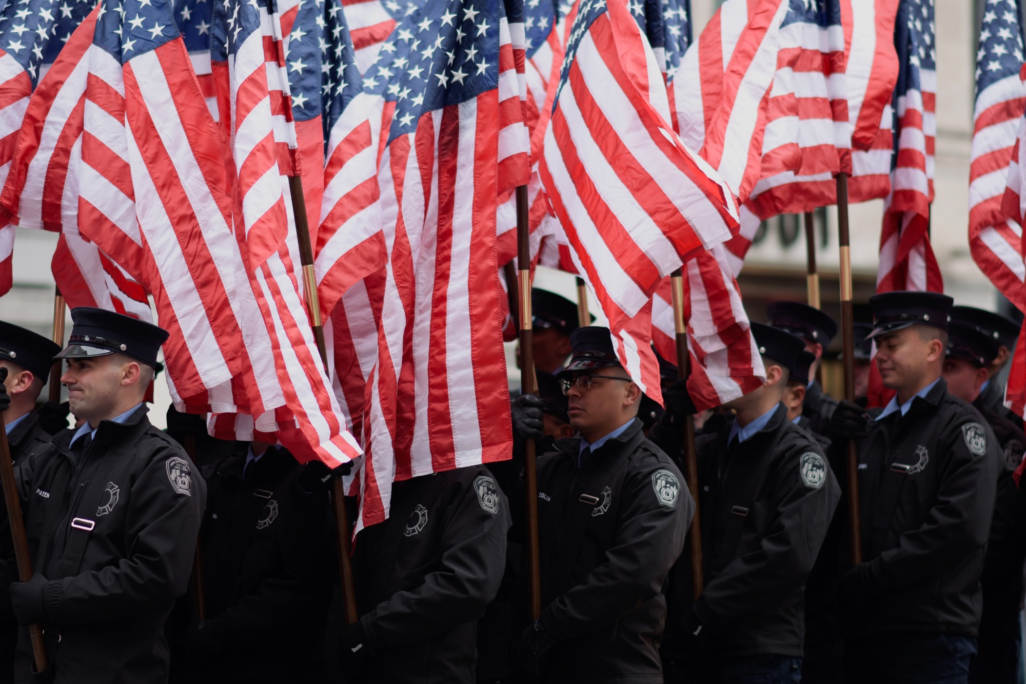 Uniformed personnel carry U.S. flags in formation.