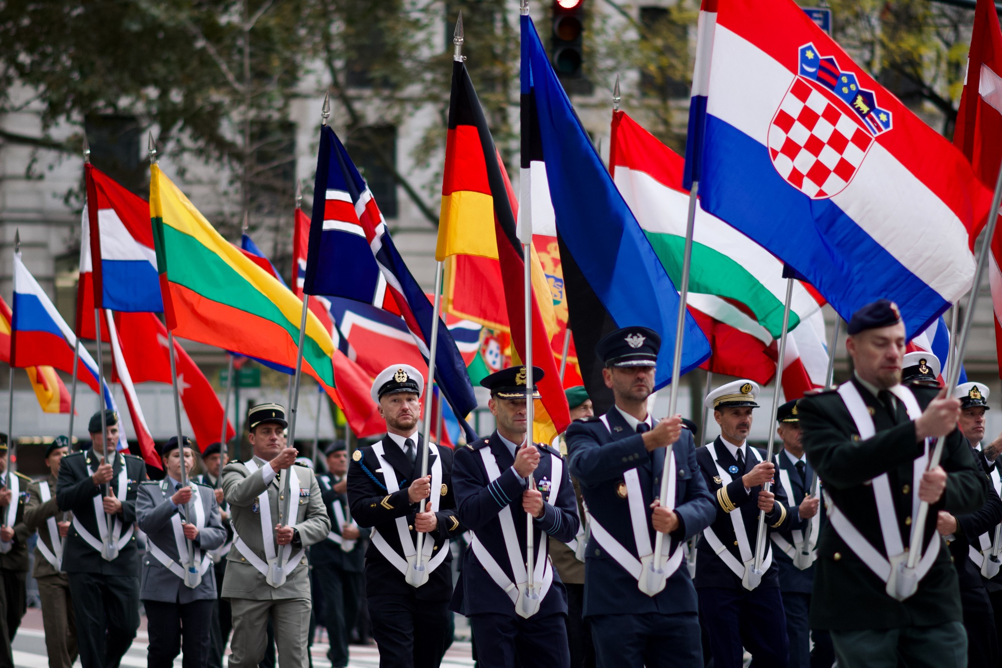 An international military delegation carries national flags along Fifth Avenue.